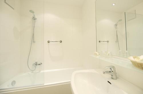 a white bathroom with a shower and a sink at Seewirt & Haus Attila in Podersdorf am See