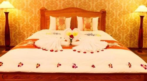 a bed with white sheets with bees on it at New Palace Bac Lieu Hotel in Bạc Liêu
