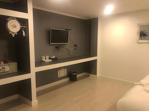 a room with a wall with a tv and a bed at white house in Phangnga