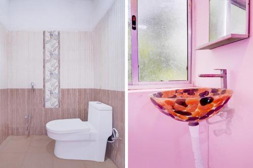 a bathroom with a toilet and a fruit bowl on a sink at Super Collection O Nagapattinam Bus Terminal Formerly Yazhisai Residency in Nāgappattinam