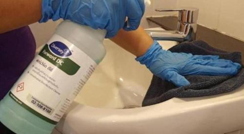 a person in blue gloves is cleaning a toilet at Wsotel Hotel in Songkhla