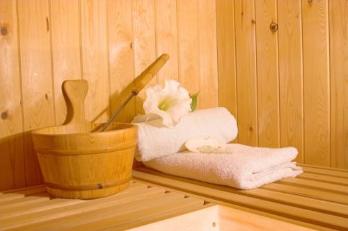 a wooden shelf with a towel and a flower in a sauna at Hotel Kormorán in Šamorín