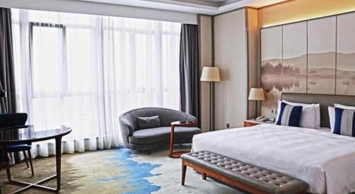 a hotel room with a bed and a chair at Rosedale Hotel Taicang in Taicang