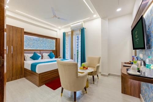 a bedroom with a bed and a desk and a tv at Honeyveils Palace Hotel - Behind Indian Expo Mart in Greater Noida