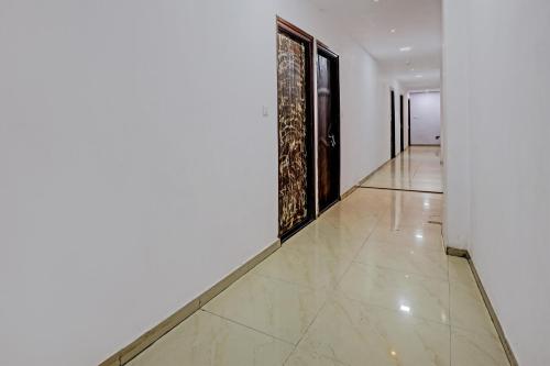 a hallway with white walls and a tile floor at Hotel O Royal Inn in Ahmedabad