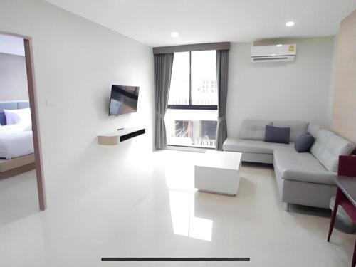 a white living room with a couch and a bed at Sattahip 9 Boutique Hotel in Pattaya Central