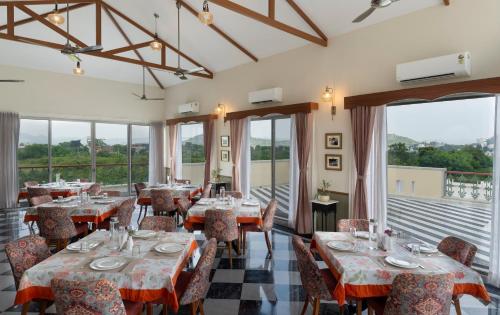 a dining room with tables and chairs and windows at Dilip Niwas in Udaipur