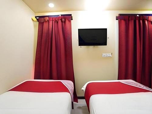 two beds in a room with red curtains and a tv at 5 Diamond in Bangkok