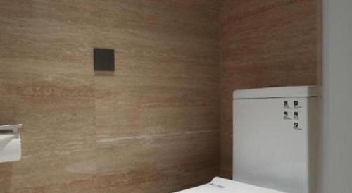 a bathroom with a white toilet and a wooden wall at Kingtown Hotel Hongqiao Shanghai in Shanghai