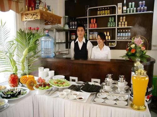 a man and a woman standing behind a counter with food at New Moon Hotel in Hanoi