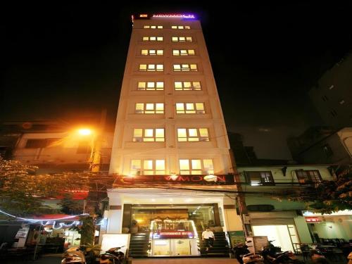a tall white building with lights on top at night at New Moon Hotel in Hanoi