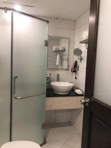 a bathroom with a sink and a glass shower door at New Moon Hotel in Hanoi