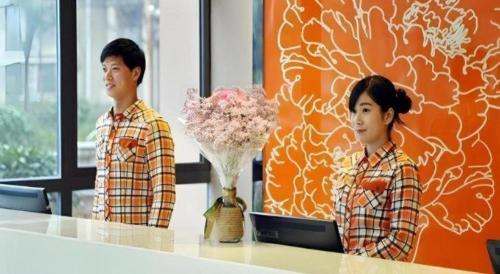 two people standing at a table with a vase of flowers at 7 Days Premium Nanjing Gaochun Beiling Road Branch in Gaochun