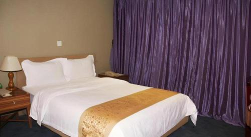 a bedroom with a large bed and purple curtains at Golden Central Hotel Shenzhen in Shenzhen