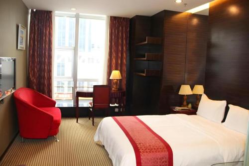 a hotel room with a bed and a red chair at Golden Central Hotel Shenzhen in Shenzhen