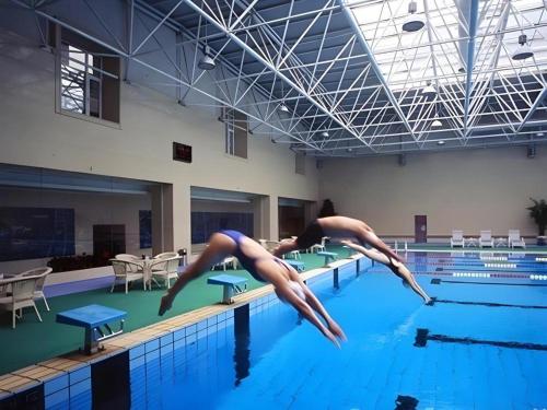 two people diving into a swimming pool at Beijing Friendship Hotel Jing Bin Building in Beijing