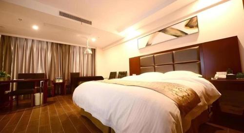 a bedroom with a large bed and a desk at GreenTree Inn Anhui Xuancheng Ningguo NinGYAng East Road Darunfa Branch in Xuanzhou