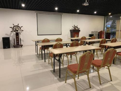 a classroom with tables and chairs and a projection screen at GreenTree Inn Taizhou New District Hospital of Renmin Hospital Mingliu Express Hotel in Jiuligou