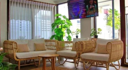a living room with wicker chairs and tables and a screen at Chiangkhan Town Hotel in Chiang Khan