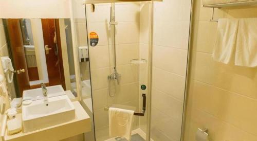 a bathroom with a glass shower and a sink at GreenTree Inn Taizhou New District Hospital of Renmin Hospital Mingliu Express Hotel in Jiuligou