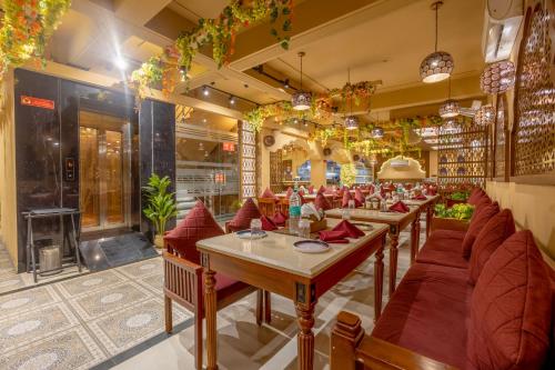 a restaurant with long tables and red chairs at Honeyveils Palace Hotel - Behind Indian Expo Mart in Greater Noida