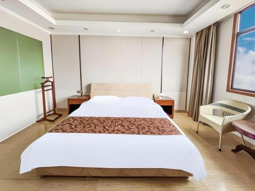 a bedroom with a large white bed and a chair at Jian Guo Grand Hotel in Vientiane