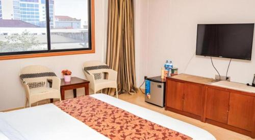 a hotel room with a large bed and a flat screen tv at Jian Guo Grand Hotel in Vientiane