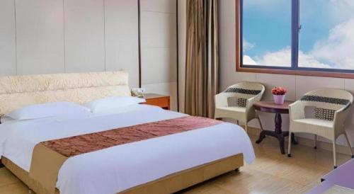 a bedroom with a bed and two chairs and a table at Jian Guo Grand Hotel in Vientiane