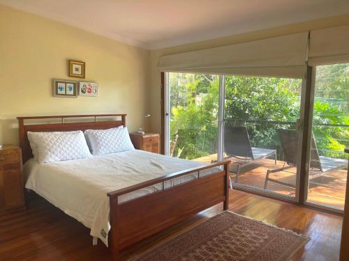 Un dormitorio con una cama y una puerta corrediza de vidrio. en Tomorrow Jervis Bay - Waterfront with Swimming Pool, en Callala Bay