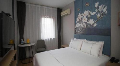 a bedroom with a white bed and a blue wall at Jinjiang Inn Tianjin Station Jinwan Square in Tianjin