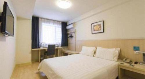 a hotel room with a bed and a desk and a television at Jinjiang Inn Tianjin Station Jinwan Square in Tianjin