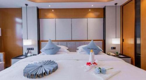 a bedroom with a large white bed with towels on it at Excemon Yuyao Hemudu Hotel in Ningbo