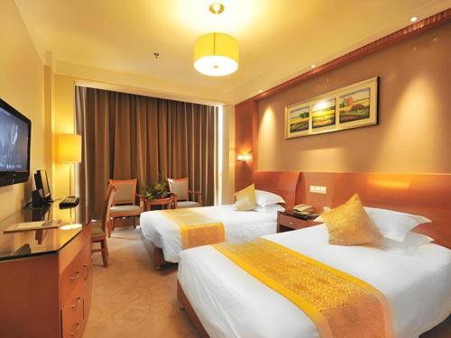 a hotel room with two beds and a television at Excemon Yuyao Hemudu Hotel in Ningbo