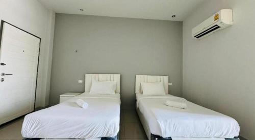 two beds in a room with white sheets at River Residence Saraburi Hotel in Sara Buri