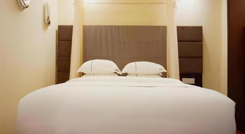 a white bed with two pillows on top of it at Jingtu hotel zhanjiang dingsheng plaza store in Zhanjiang