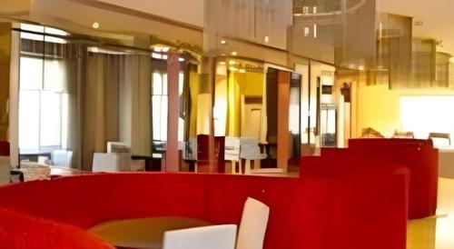a room with a red couch and a table and chairs at Jinjiang Inn Wenzhou Shuangyu The Terminal in Wenzhou