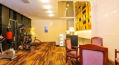 a room with a gym with a treadmill and chairs at Jinjiang Metropolo Hotel - Taizhou Wanda Plaza in Taizhou