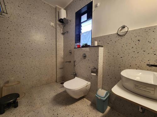 a bathroom with a toilet and a sink at Beachside 1BHK Apartment - Pool, Gym & Modern Comforts, Candolim in Candolim