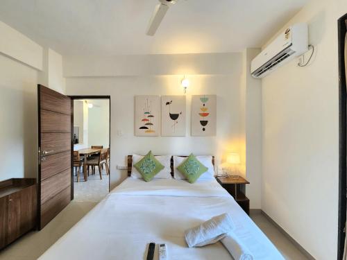 a bedroom with a large white bed and a table at Beachside 1BHK Apartment - Pool, Gym & Modern Comforts, Candolim in Candolim