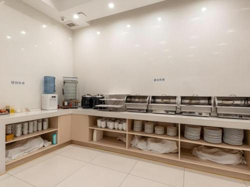 a kitchen with a counter with dishes on shelves at GreenTree Inn Nantong University Industrial Expo City Express Hotel in Nantong