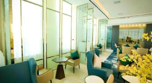 a waiting room with blue chairs and tables and windows at Jinjiang Metropolo Hotel - Turpan Administration Center in Turfan