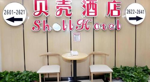 a table and two stools in front of a sign at Shell Taiyuan South Station Shanxi University Hotel in Taiyuan