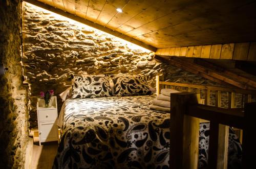 a bedroom with a bed in a stone wall at Casa Turística Viladonatus (Ribeira Sacra) in Doade