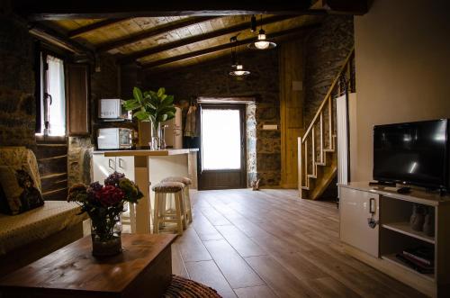 a living room with a wooden floor and a television at Casa Turística Viladonatus (Ribeira Sacra) in Doade