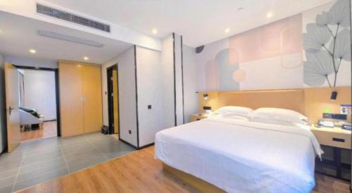 a bedroom with a large white bed and a bathroom at GreenTree Inn Ganzhou Gan County Bus Station in Ganzhou
