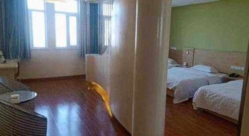 a hotel room with two beds and a window at 7 Days Inn Yining Xintiandi in Kipekyüzi