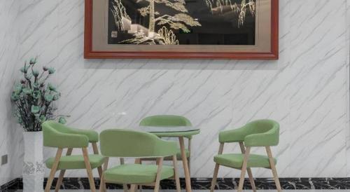 four green chairs and a table in a room at GreenTree Inn Wuhu Eshan Road University City in Wuhu