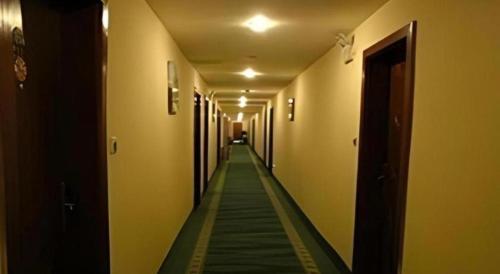 a long hallway with yellow walls and a green floor at GreenTree Inn Jinan Bus Terminal in Jinan