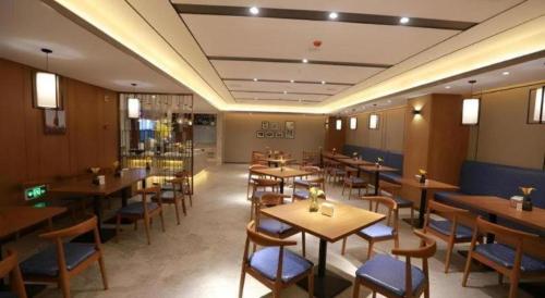 a restaurant with tables and chairs in a room at Yitel Collection Harbin Railway Station Museum Metro Station in Harbin