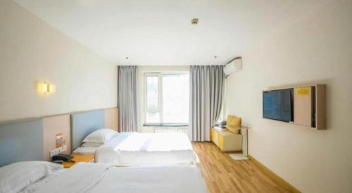 a hotel room with two beds and a tv at 7 Days Inn Harbin West Railway Station in Harbin